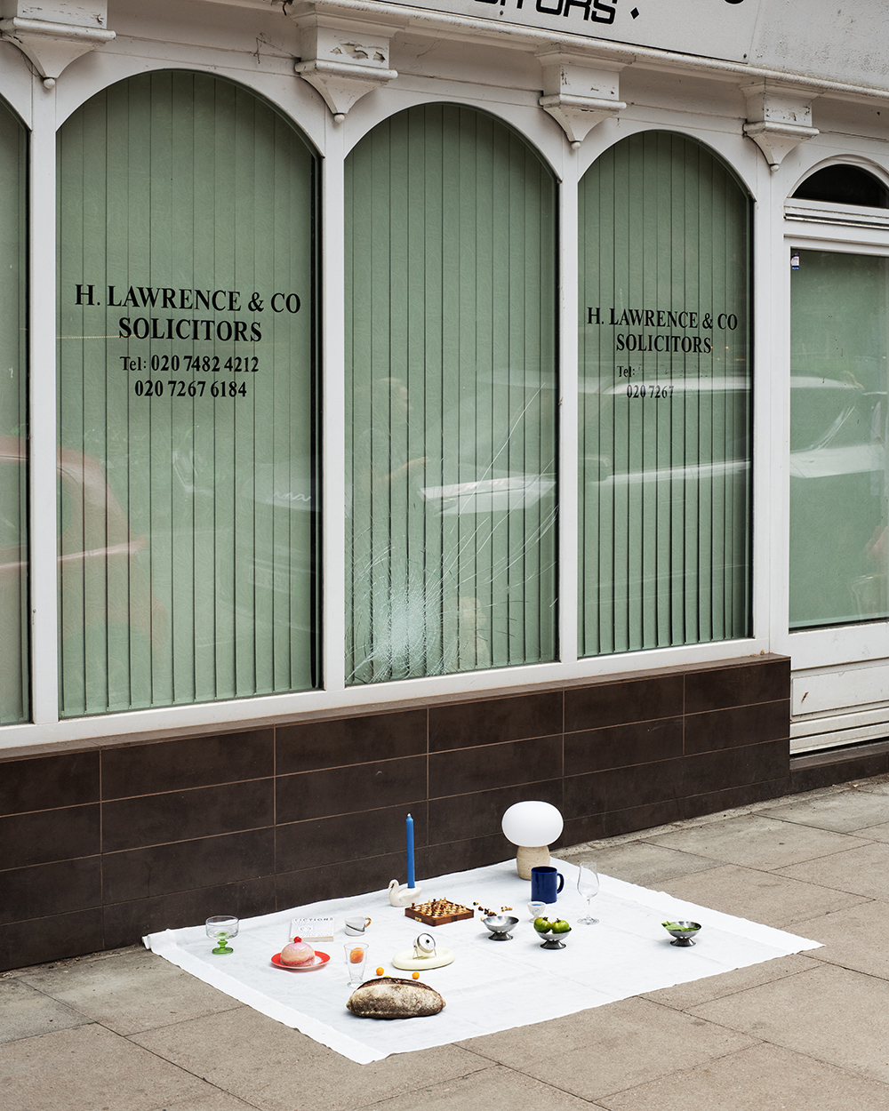 A picnic in front of a solicitor's office. The storefront has a broken window.
